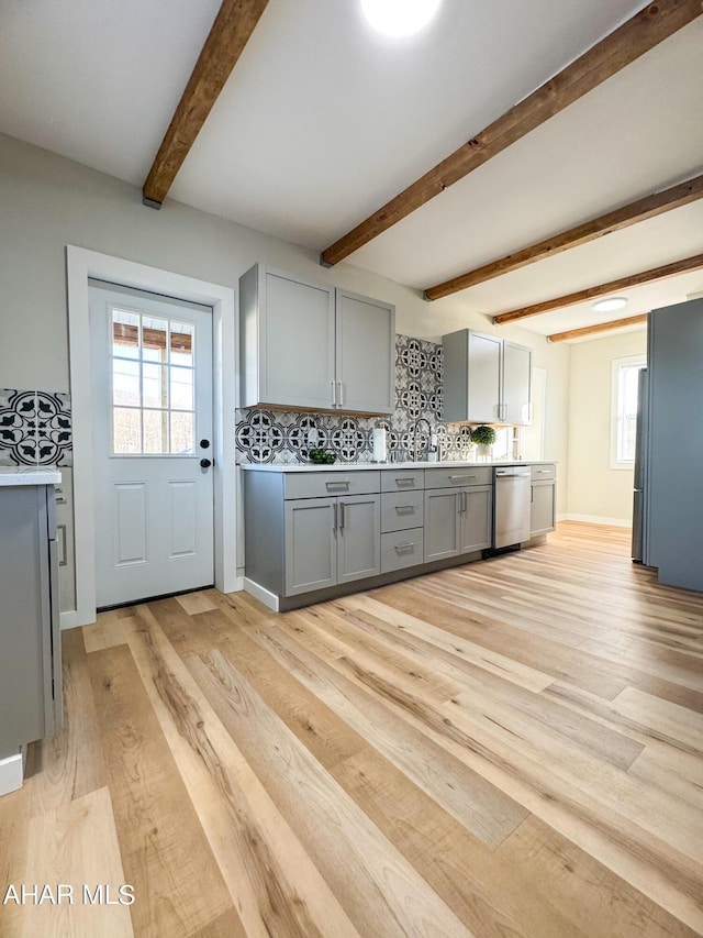 kitchen featuring gray cabinets, backsplash, beam ceiling, light hardwood / wood-style floors, and stainless steel dishwasher