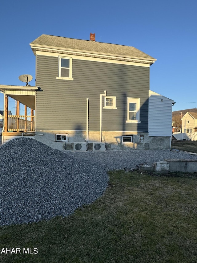 back of property featuring ac unit and a lawn