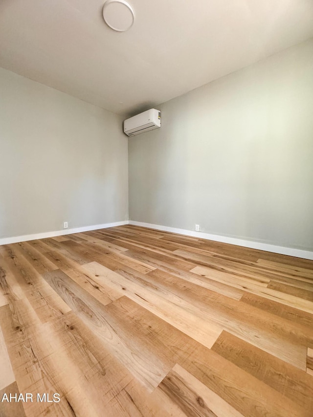 unfurnished room featuring hardwood / wood-style flooring and a wall unit AC