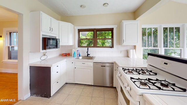 1113 Broadway, Altoona, PA 16601 - kitchen with white gas stove, dishwasher, black microwave, tasteful backsplash, and white cabinets