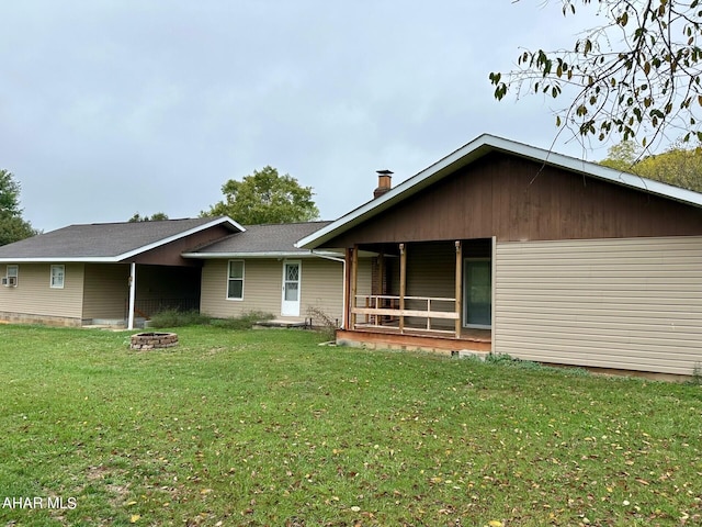 back of property featuring a lawn and an outdoor fire pit