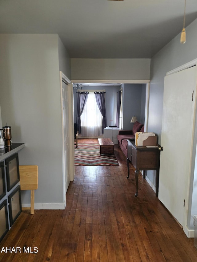 hall featuring hardwood / wood-style flooring and baseboards