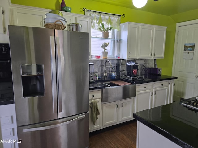 kitchen featuring dark countertops, a sink, white cabinetry, and stainless steel fridge with ice dispenser