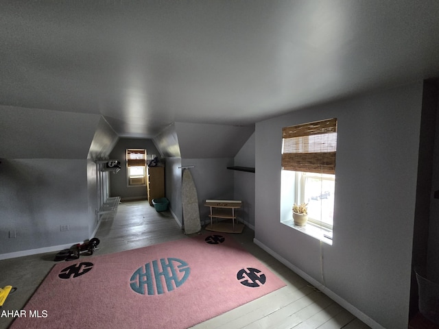 additional living space featuring baseboards, wood finished floors, and vaulted ceiling