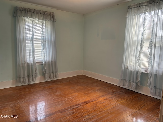 unfurnished room featuring a wealth of natural light and hardwood / wood-style floors