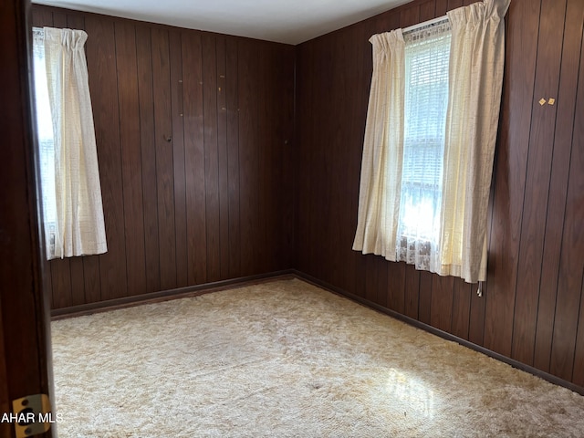 spare room featuring light colored carpet and wood walls