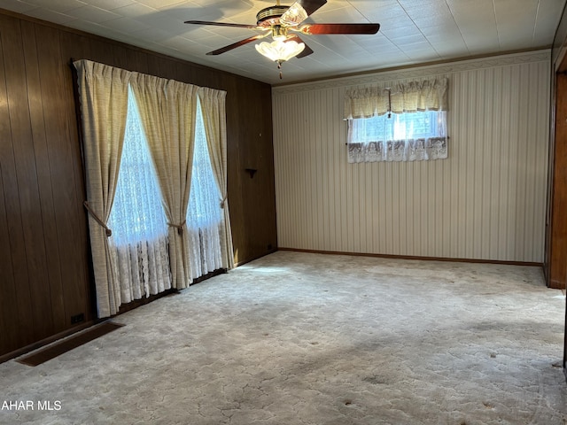 carpeted spare room featuring ceiling fan and wood walls