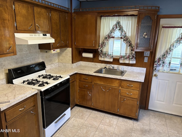 kitchen featuring decorative backsplash, white range, and sink