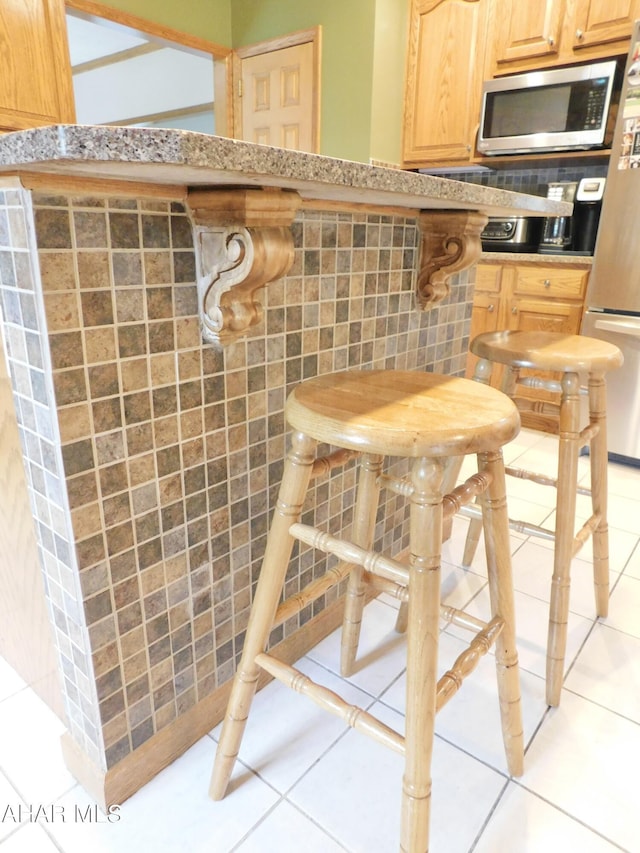 kitchen with light tile patterned flooring, backsplash, and appliances with stainless steel finishes