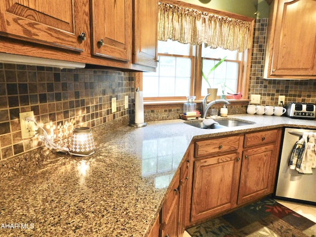 kitchen with backsplash, dishwasher, light stone countertops, and sink