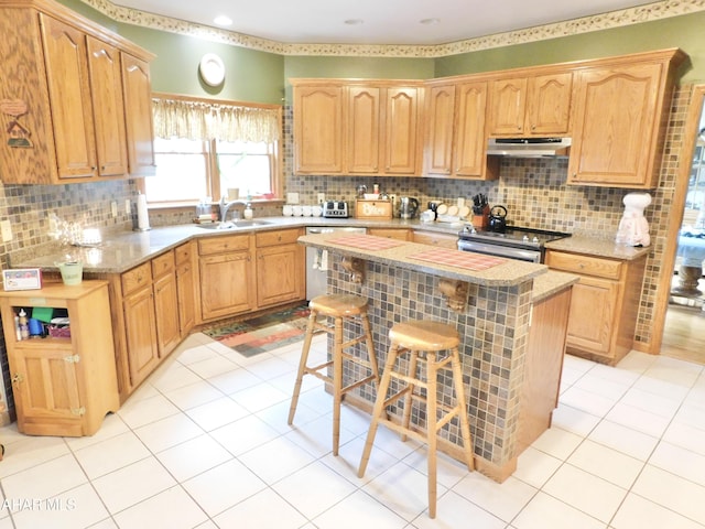 kitchen featuring a center island, sink, decorative backsplash, a kitchen bar, and stainless steel appliances