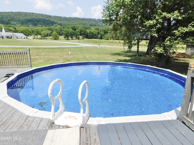 view of swimming pool with a lawn and a wooden deck