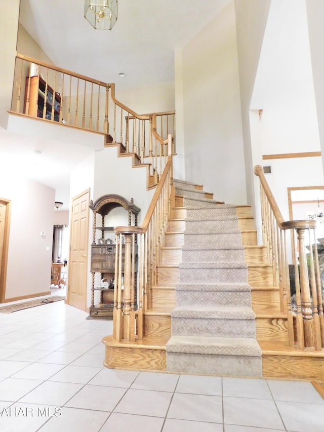 stairway featuring tile patterned flooring and a towering ceiling