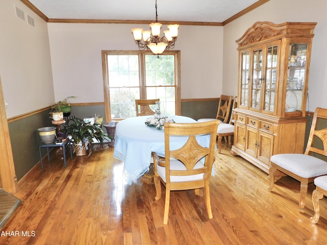 dining space featuring a chandelier, crown molding, and light hardwood / wood-style floors