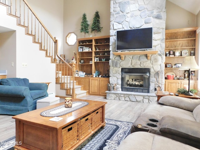 living room featuring a fireplace, light hardwood / wood-style flooring, and high vaulted ceiling