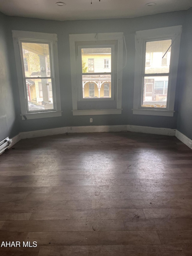 empty room with dark wood-type flooring and baseboards