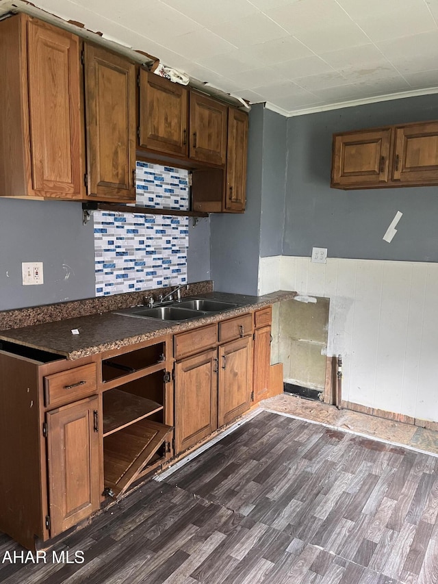 kitchen featuring a sink, brown cabinetry, dark countertops, and dark wood-style floors