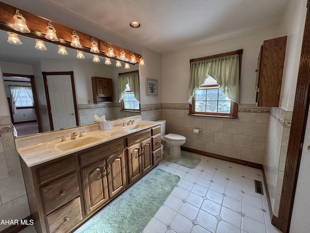 bathroom with vanity, toilet, and tile walls