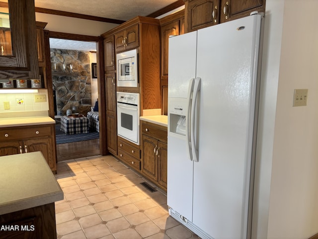 kitchen with backsplash, white appliances, and ornamental molding