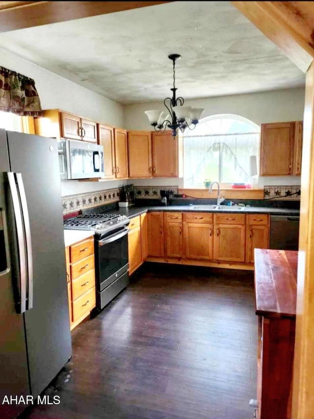 kitchen featuring stainless steel appliances, dark wood-type flooring, a sink, decorative backsplash, and pendant lighting