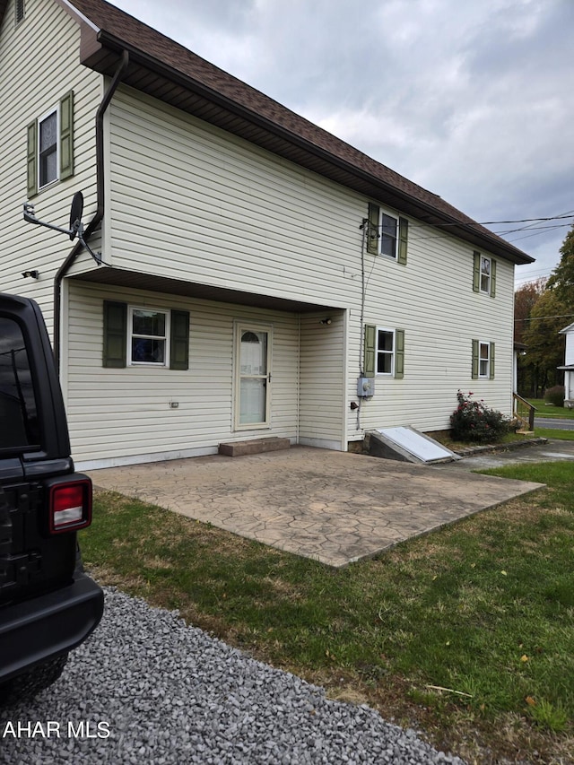 back of property featuring a patio area and a yard