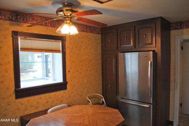 kitchen featuring freestanding refrigerator, dark brown cabinets, and wallpapered walls