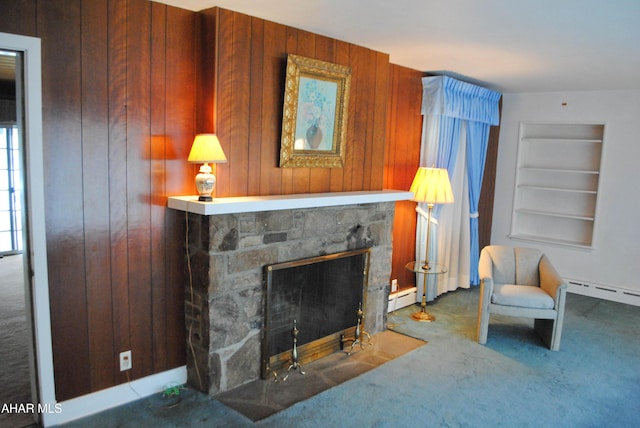 sitting room with carpet, baseboard heating, a stone fireplace, wood walls, and built in shelves