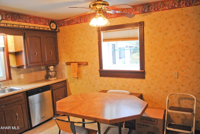 kitchen with wallpapered walls, dishwasher, backsplash, light countertops, and a sink