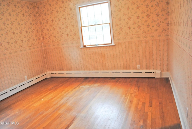 spare room with wood finished floors and wallpapered walls