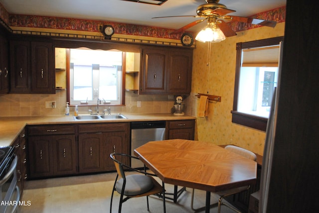 kitchen with stainless steel appliances, light countertops, a sink, dark brown cabinets, and wallpapered walls