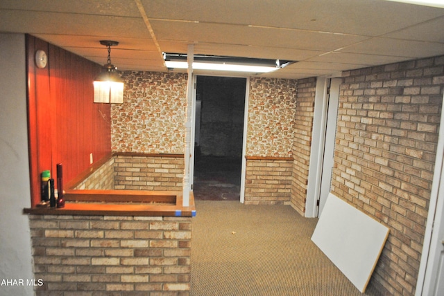 interior space featuring carpet, brick wall, and a drop ceiling