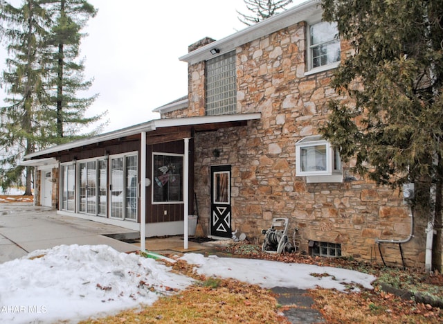 exterior space with stone siding and a sunroom