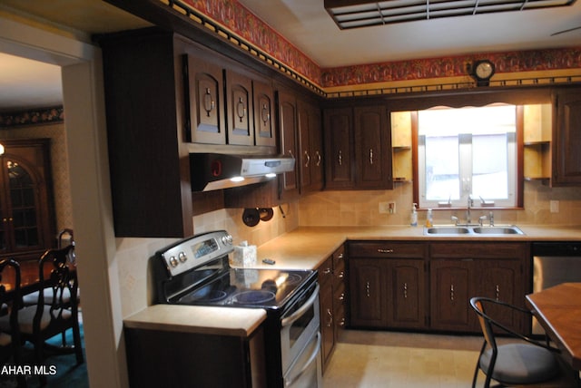 kitchen with light countertops, appliances with stainless steel finishes, a sink, and under cabinet range hood