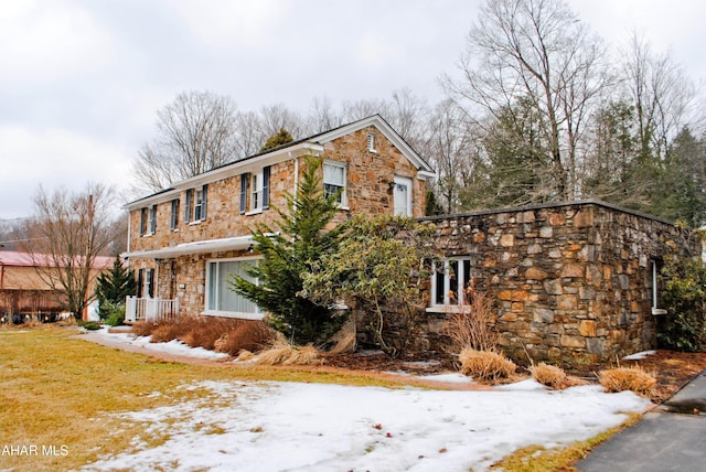 view of front facade featuring stone siding and a lawn