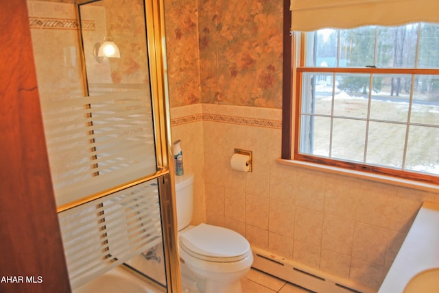 bathroom featuring a shower with door, tile walls, toilet, a baseboard heating unit, and tile patterned flooring