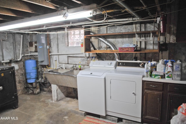 laundry room with laundry area, electric panel, a heating unit, washing machine and dryer, and a sink