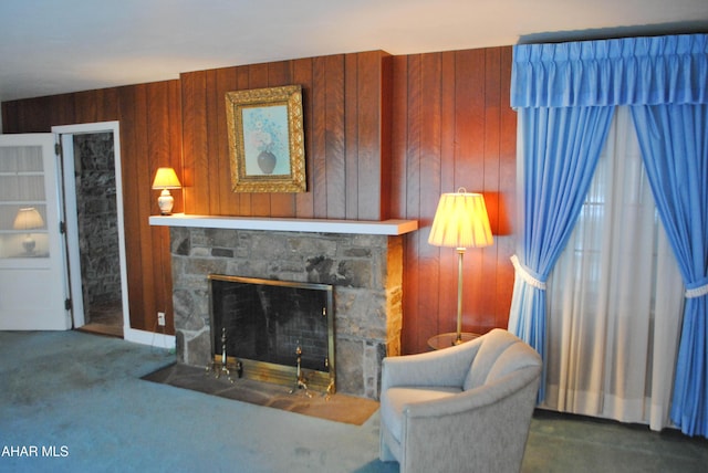 carpeted living room featuring wood walls and a fireplace