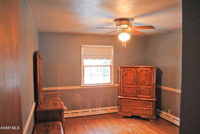 bedroom featuring ceiling fan, a baseboard heating unit, and wood finished floors