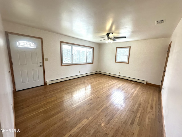 entrance foyer with a baseboard heating unit, baseboards, visible vents, ceiling fan, and wood-type flooring