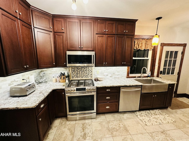 kitchen featuring pendant lighting, stainless steel appliances, sink, and backsplash