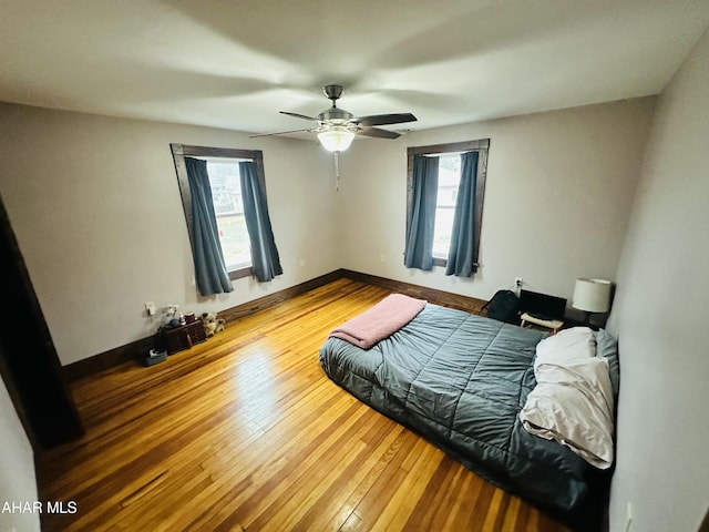 bedroom with ceiling fan, hardwood / wood-style floors, and multiple windows