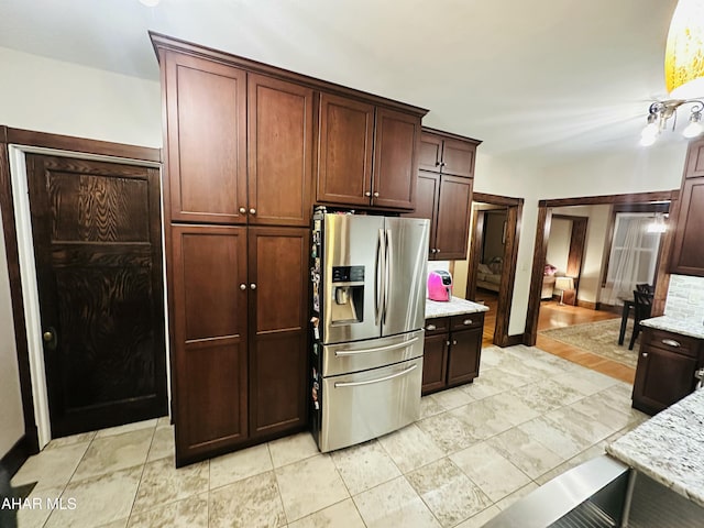 kitchen featuring light stone countertops and stainless steel refrigerator with ice dispenser