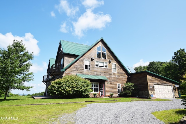 view of front of house featuring a garage, a balcony, and a front lawn