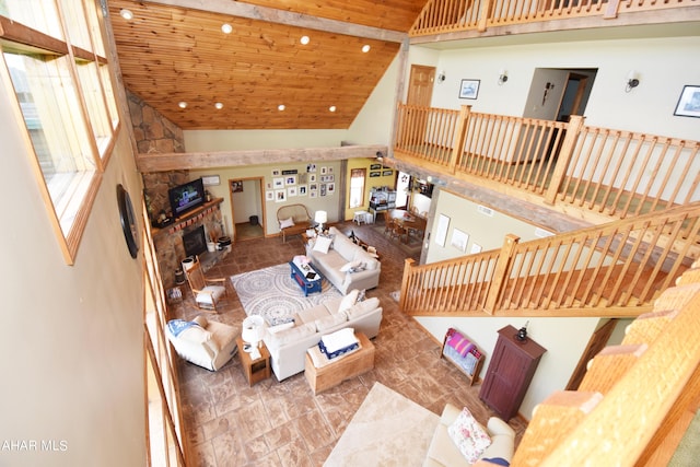 living room featuring a stone fireplace, a wealth of natural light, high vaulted ceiling, and wooden ceiling