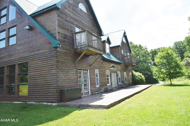 rear view of property with a balcony, a yard, and a patio