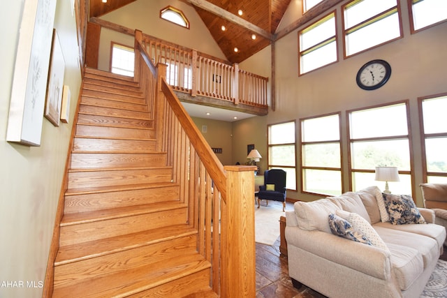 stairway with beamed ceiling, plenty of natural light, hardwood / wood-style flooring, and high vaulted ceiling