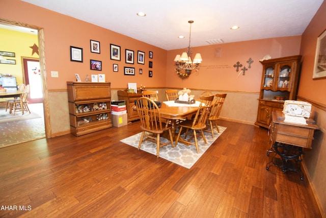 dining area featuring wood-type flooring and a notable chandelier