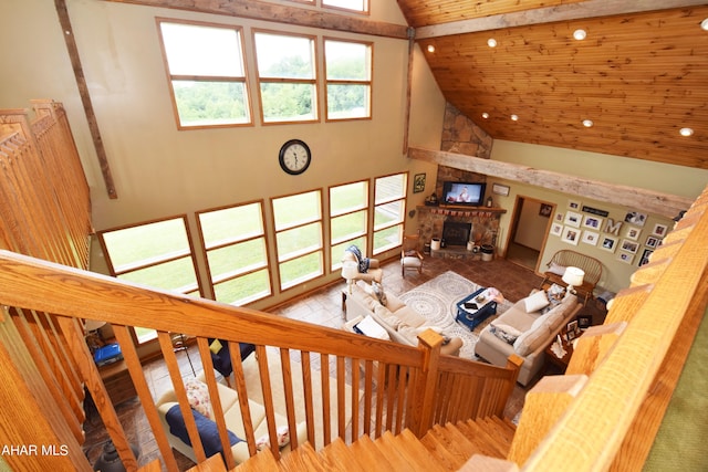 living room with hardwood / wood-style floors, a stone fireplace, beamed ceiling, and high vaulted ceiling