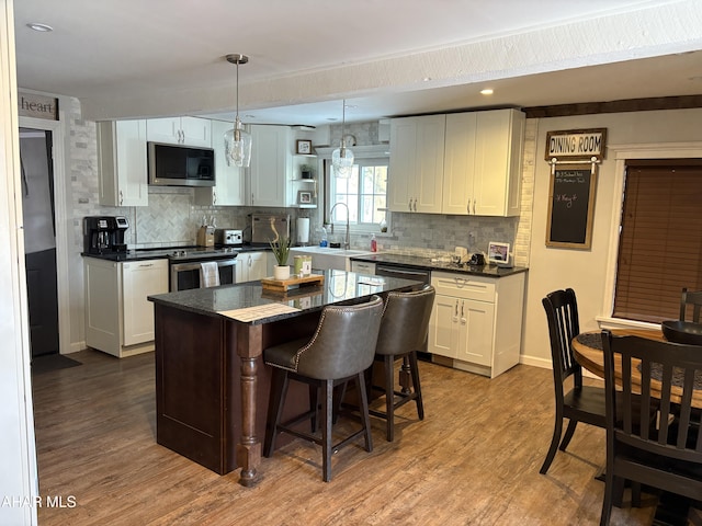 kitchen featuring decorative light fixtures, white cabinetry, a center island, light hardwood / wood-style floors, and stainless steel appliances