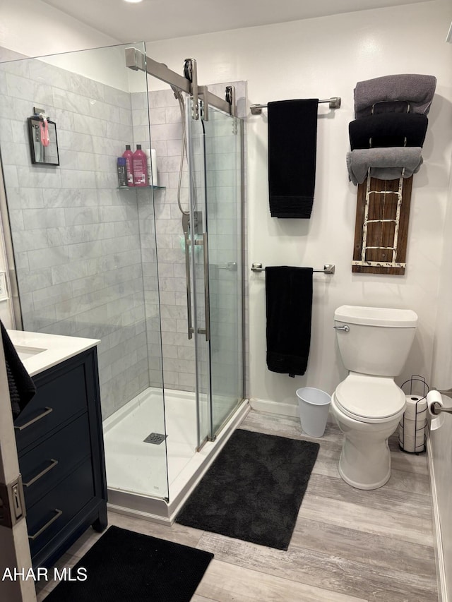 bathroom with vanity, toilet, hardwood / wood-style floors, and a shower with shower door